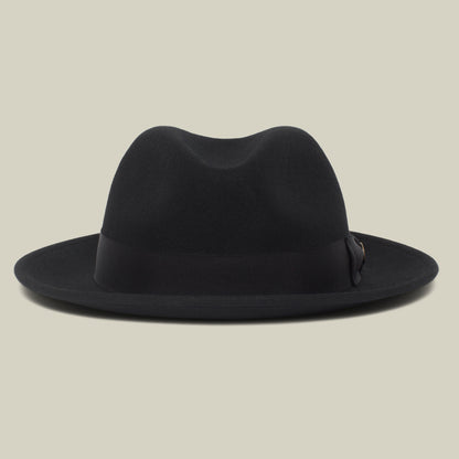 Dean the Butcher by Goorin Bros. is a black, American-made fedora featuring a wide brim and sleek grosgrain hatband, shown against a plain beige background.