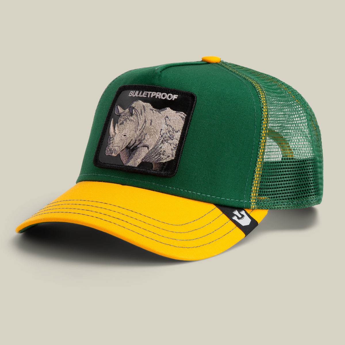 The Farm's "The Bulletproof Rhino" is a green and yellow trucker hat with mesh back and a front patch showing a rhino and BULLETPROOF. All sales are final.