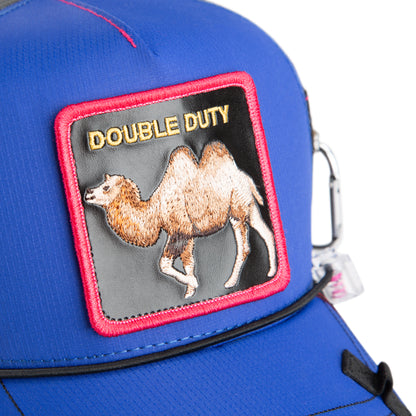 A blue, water-resistant hat from The Farm called “Oversized Package,” featuring a red-bordered patch with a camel and the words DOUBLE DUTY embroidered at the top.