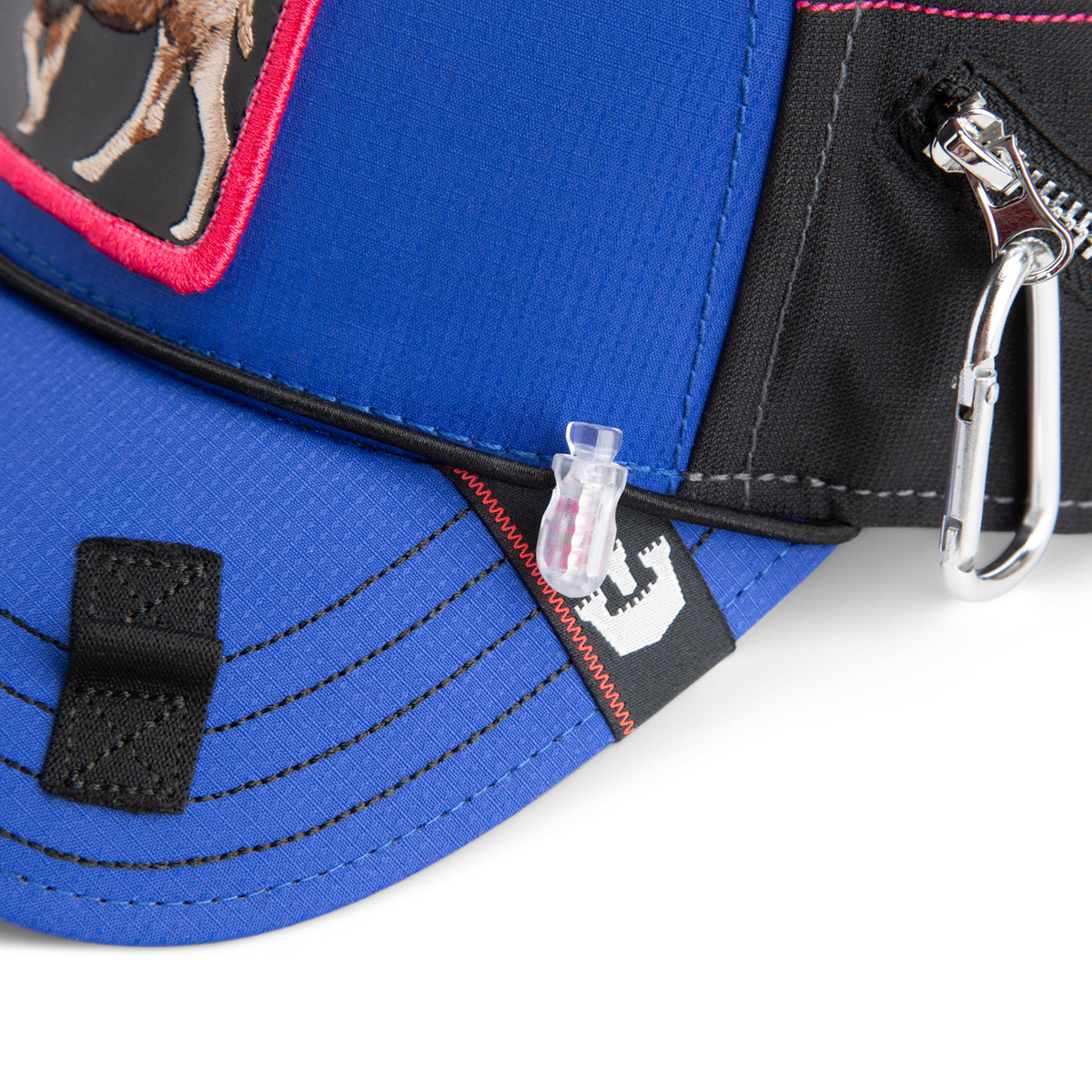 Close-up of The Farm’s “Oversized Package” cap in blue and black, featuring a water-resistant design with a horse patch, an extra-wide brim, and added functionality from an attached carabiner and plastic toggle.