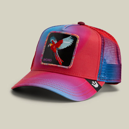The Farm's "Bird is the Word" trucker hat features red and blue mesh, a flying parrot patch, and "WORD" embroidered on the front. All sales are final.