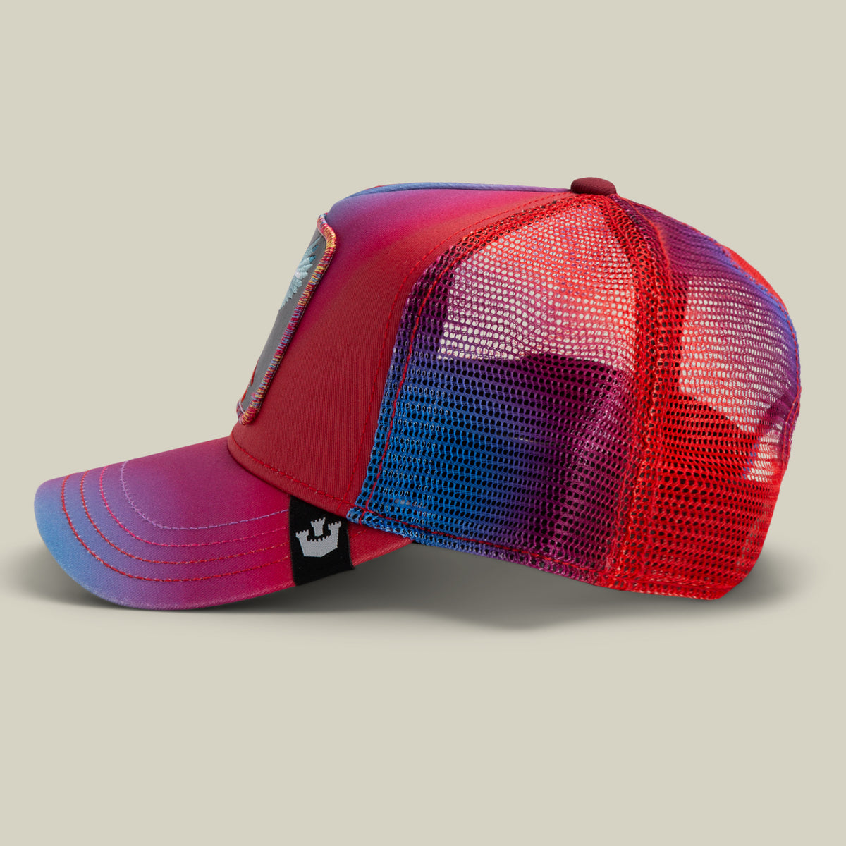Bird is the Word by The Farm: a red and blue gradient mesh trucker hat with a front patch and black side tag, shown on a neutral background. All sales are final.