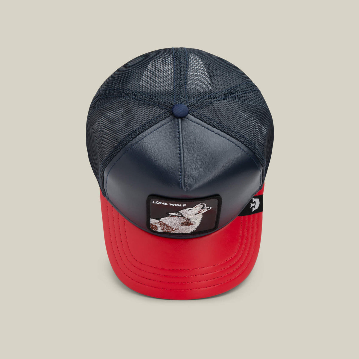The Farm’s Shleather Wolf is a navy and red trucker hat with a mesh back and front patch featuring a wolf and Lone Wolf text—ideal for those who love bold, trendy style.