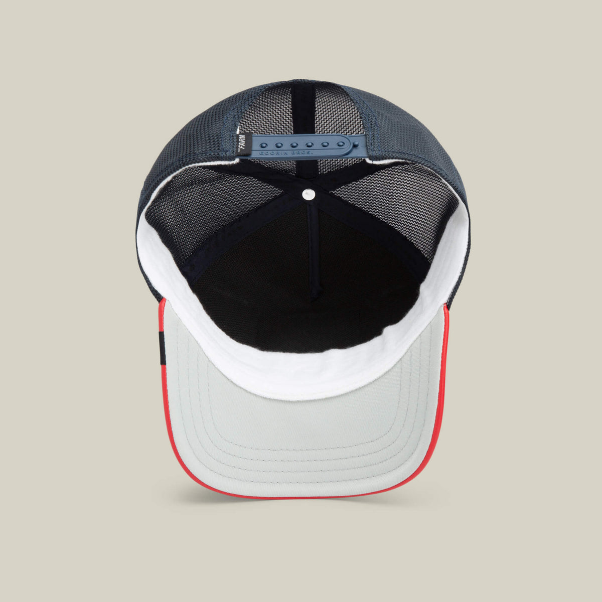 A look inside The Farm’s Shleather Wolf: a mesh trucker cap featuring a gray brim, red edge, white front panel, black interior, and adjustable snapback closure—designed for bold, fashion-forward style.