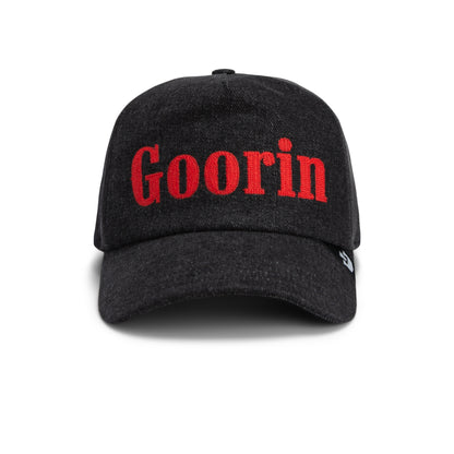 A front-view image of the Smoke Signal baseball cap by Goorin Bros., featuring the word “Goorin” embroidered in bold red letters on the front, crafted from premium black stonewashed denim.