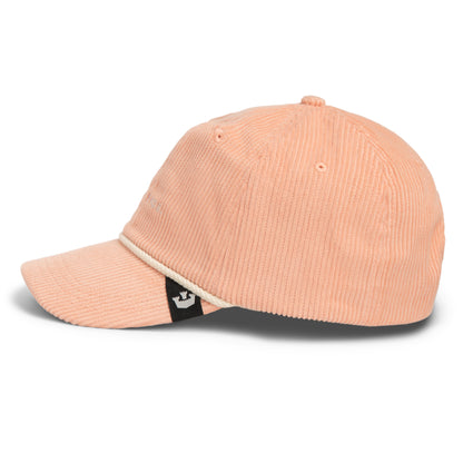 Side view of The Clubhouse by Goorin Bros., crafted from light peach wide wale corduroy, featuring a curved brim, white rope detail above the visor, and a small black and white logo tag on the left side—an understated nod to quiet luxury.