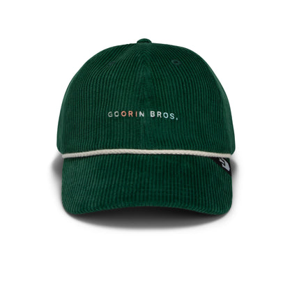 Introducing The Clubhouse by Goorin Bros.: a dark green wide wale corduroy baseball cap, featuring a white rope across the brim and “GOORIN BROS.” elegantly embroidered on the front, exuding quiet luxury in every detail.