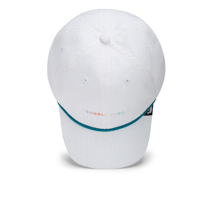 The Clubhouse by Goorin Bros. is a white baseball cap with a curved brim, accented with blue trim and small multicolored text on the front, embodying quiet luxury. Crafted from wide wale corduroy for a unique texture and featuring a black side tag, this cap is displayed against a plain white background.