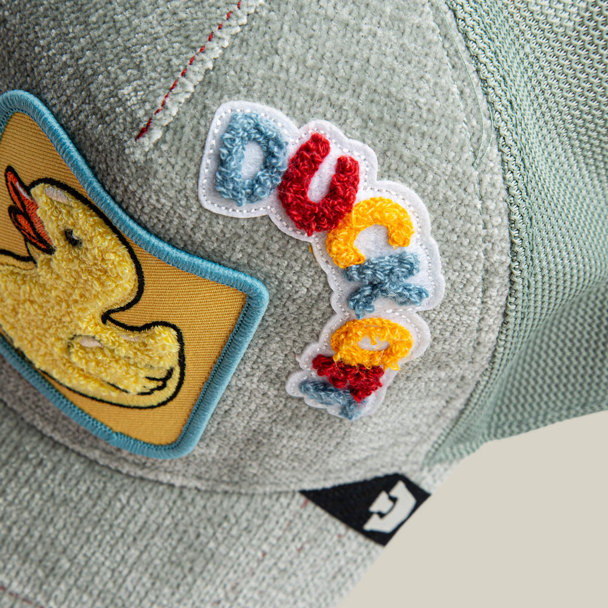 A close-up of the Goorin Bros. Ducking Autocorrect cap—a light gray textured hat with a yellow duck patch and "duck" embroidered in colorful letters, making it a playful and funny addition to any novelty hat collection.