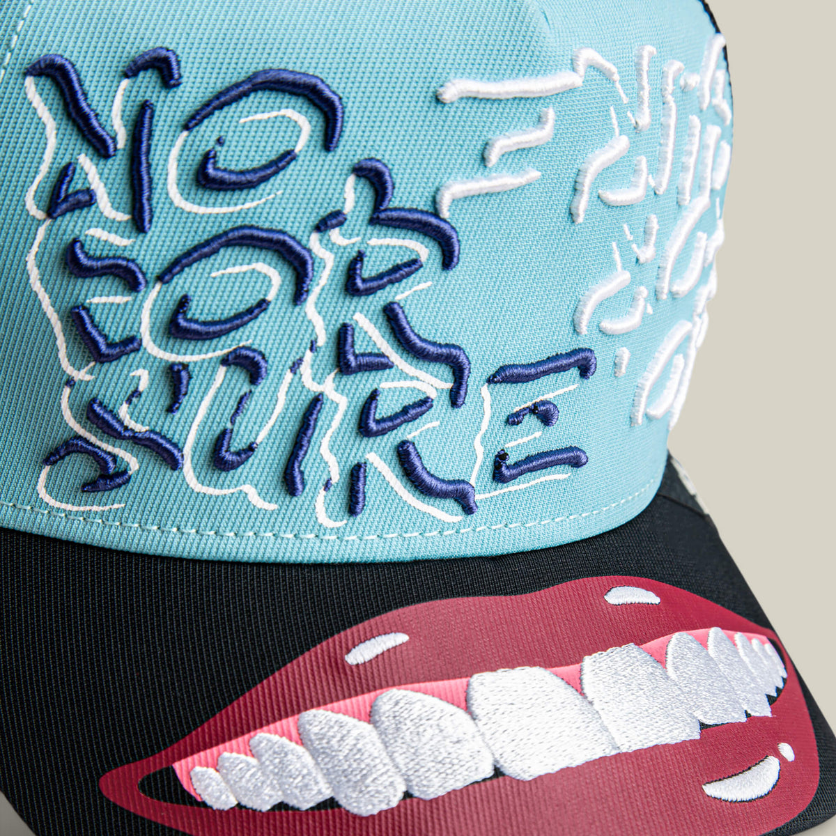 The Means Understood hat by Goorin Bros. features blue and black colors, bold “NO FOR SURE” embroidery, and big smiling lips on the brim—a fun choice for confident style. All sales are final.