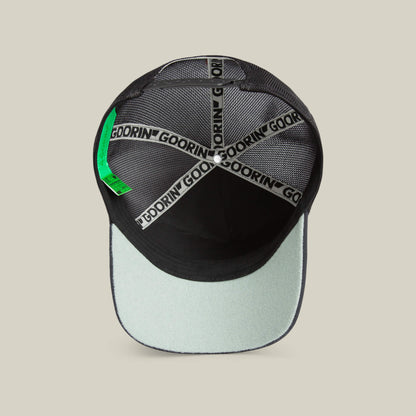 A top-down view of the inside of the Means Understood cap by Goorin Bros. in black and light gray highlights quality details like Goorin branding on the seams and a green tag. Please note all sales are final.