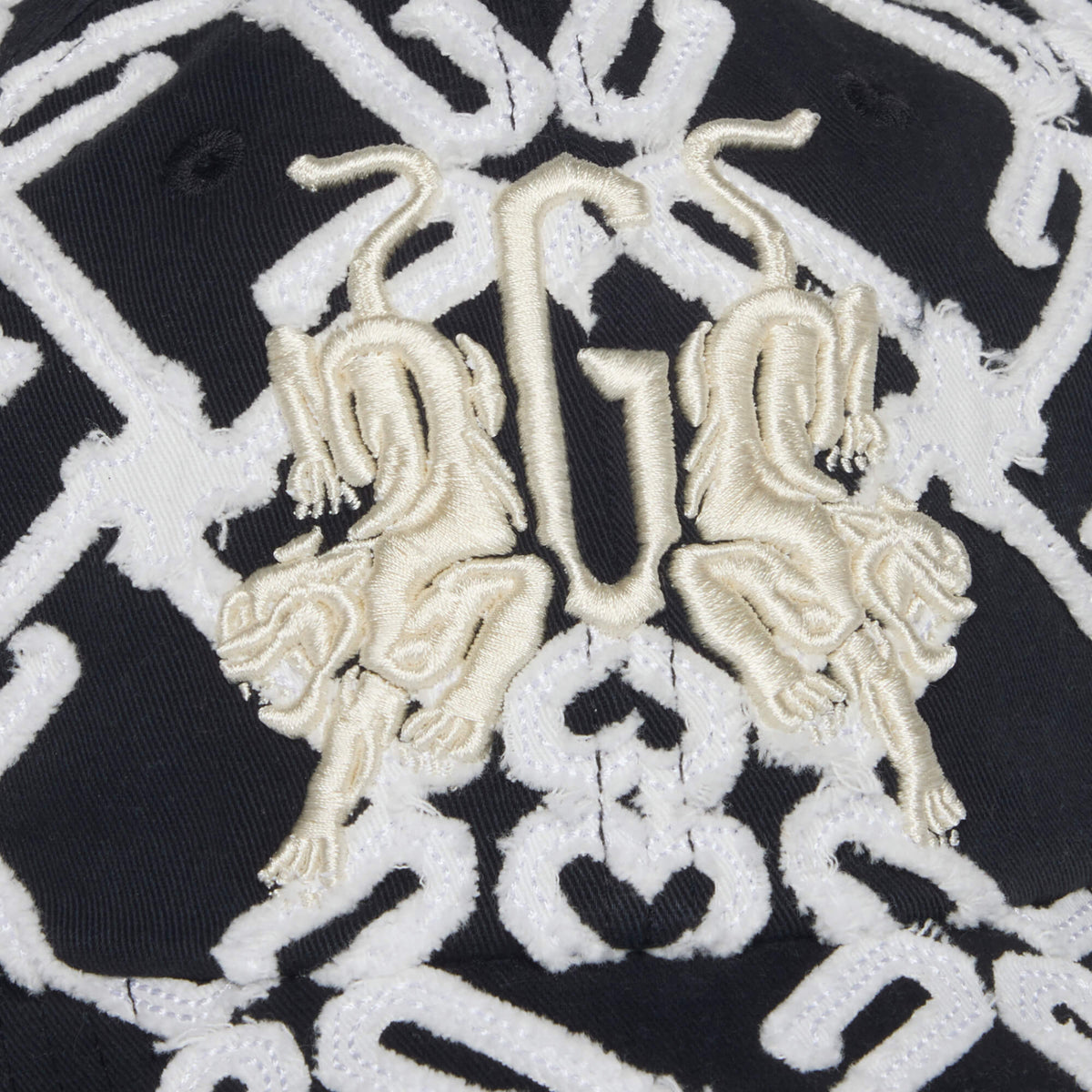 Close-up of the Goorin Bros. Future Baby Daddy cap: black fabric with all-over white geometric embroidery and two gold lions facing a stylized G in the center, showcasing the new branding.