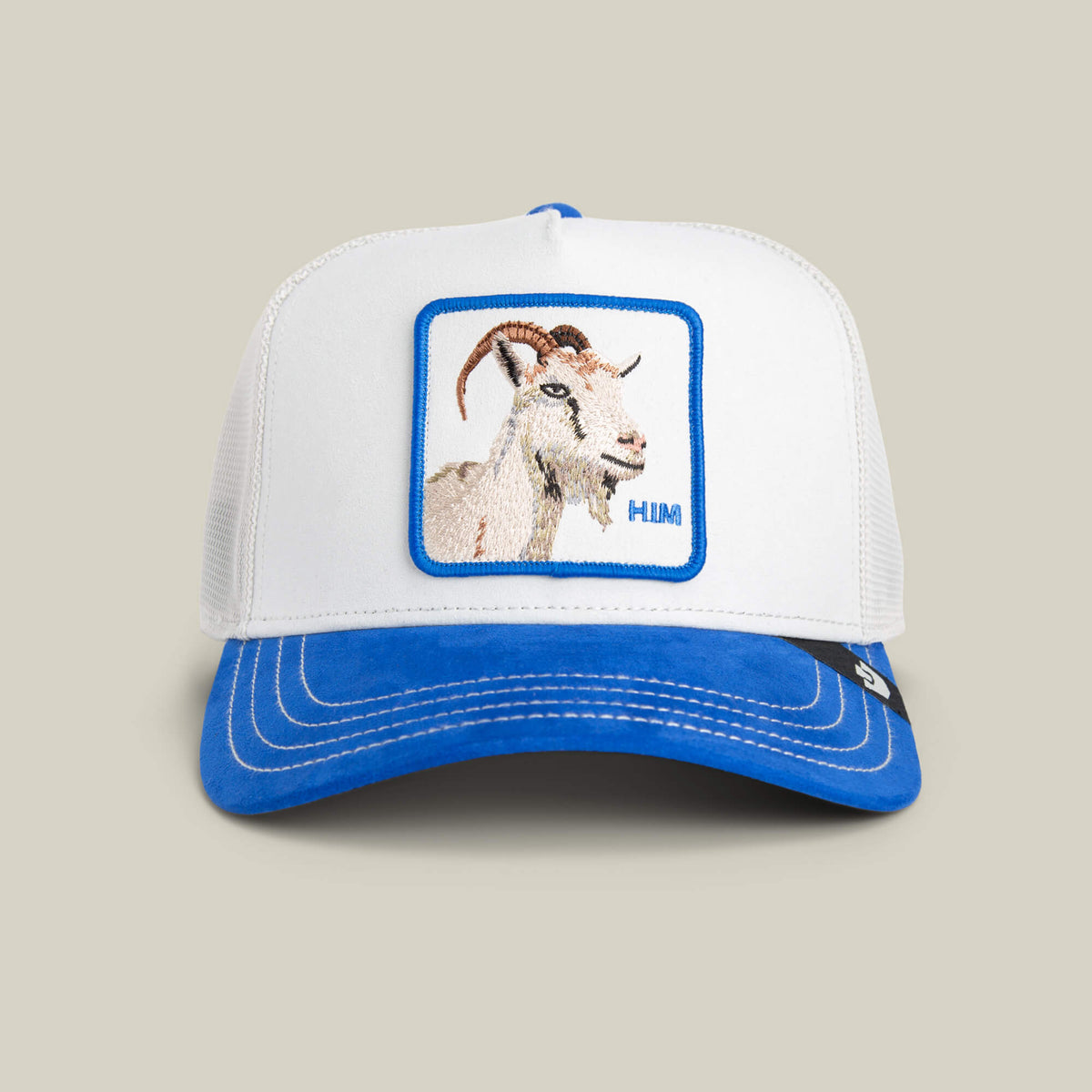 The Suede Goat by Goorin Bros. is a white crown hat with an electric blue brim, featuring a goat patch and "HIM" embroidered on the front.
