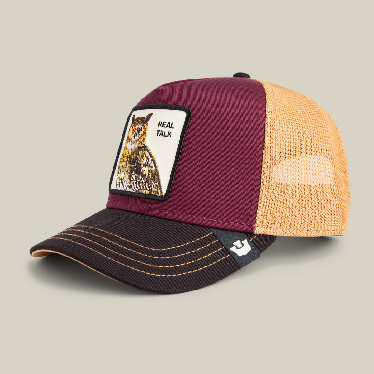 The Goorin Bros. Tricolor Owl trucker cap features maroon and yellow mesh with a bold “REAL TALK” owl patch on the front—an eye-catching statement piece.