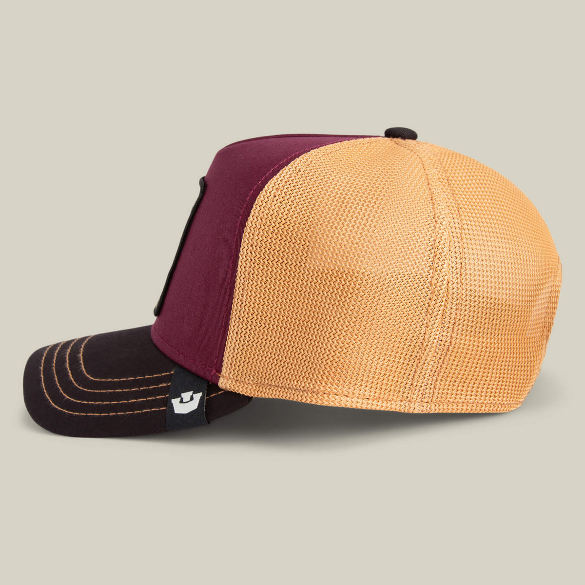 The Goorin Bros. Tricolor Owl trucker hat showcases a dark brown front, burgundy panel, and yellow mesh back, presented in profile against a plain background.