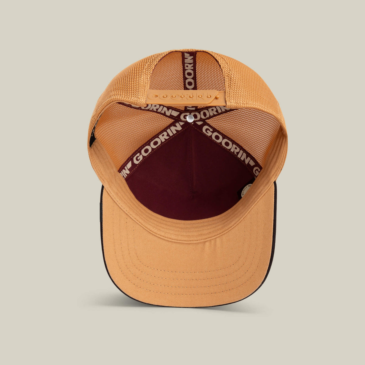 The Tricolor Owl by Goorin Bros. is a tan and maroon mesh trucker hat shown from above, featuring an adjustable snapback strap, honey mesh panels, a black brim, and GOORIN branding on the inner band.