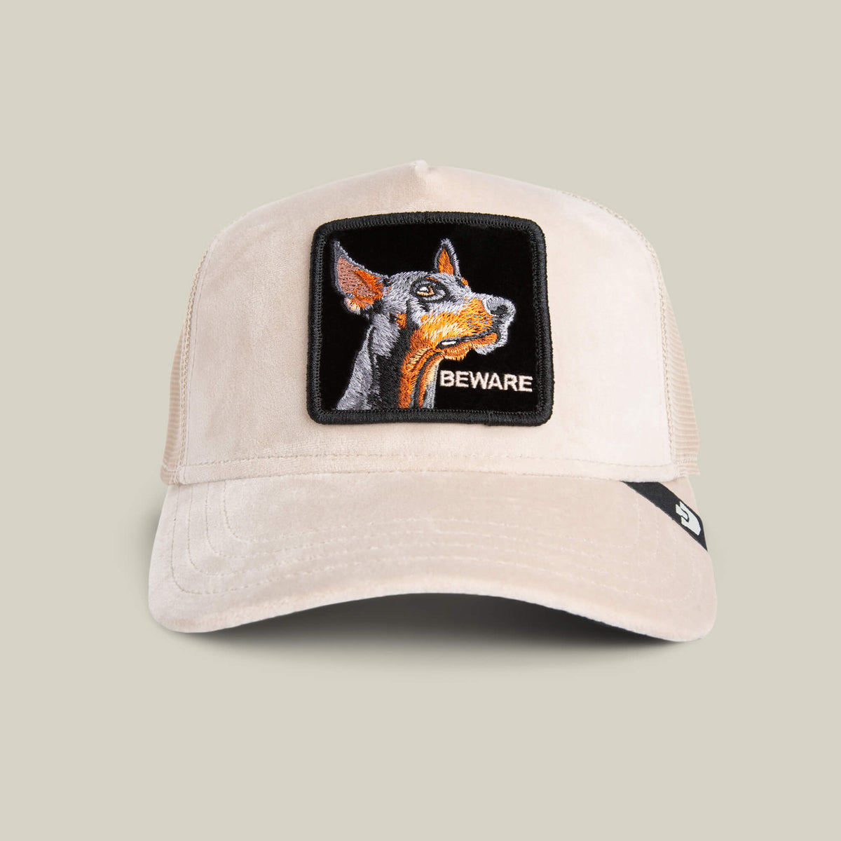 The Goorin Bros. Velour Doberman cap in BISCUIT features a mesh back, a playful Doberman patch, and "BEWARE" on the front—a luxury statement hat blending standout detail with style.