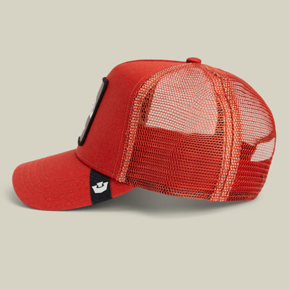 The Extinct Skull by Goorin Bros is a bright red trucker hat with mesh back panels and a black accent stripe on the side featuring a small white logo patch, displayed against a neutral studio background.