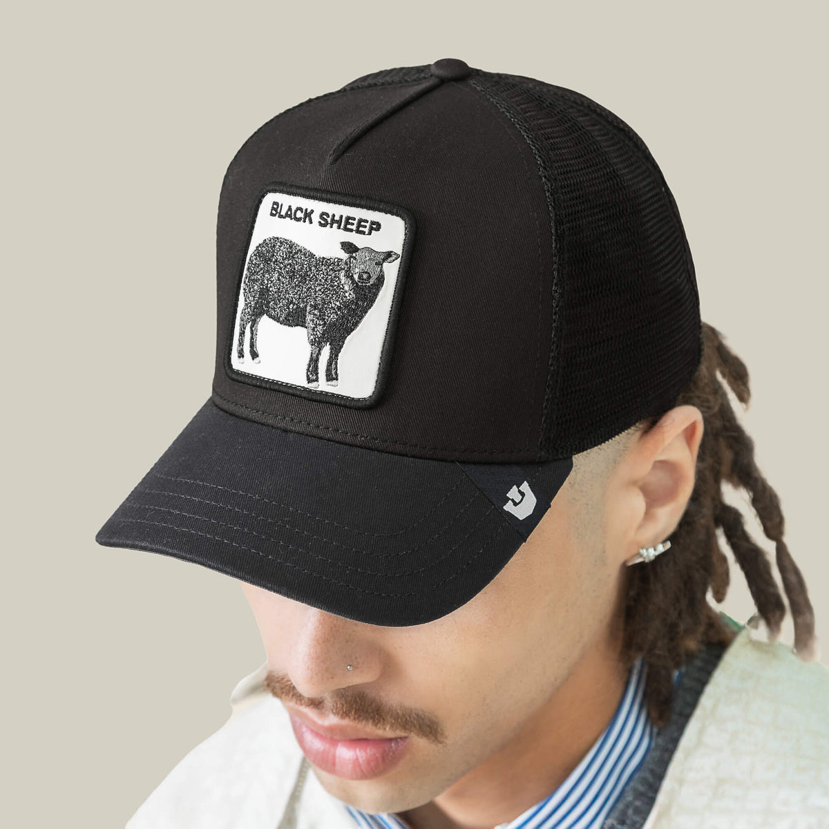 The Goorin Bros. Black Sheep Trucker features a bold patch with a black sheep and "BLACK SHEEP" text, perfect for those who dare to stand out.