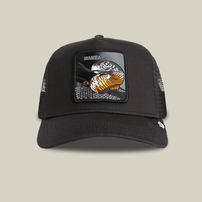 The Goorin Bros. Mamba Trucker is a black mesh trucker hat featuring a detailed front patch with an orange and black mamba snake graphic and text, displayed on a beige background.