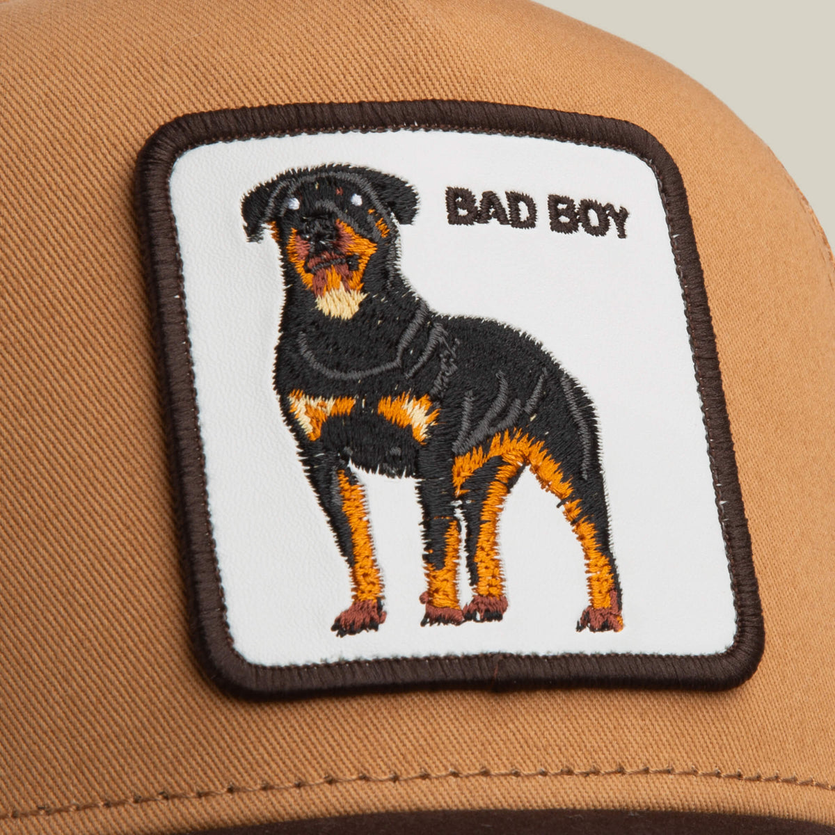The Bad Boy Trucker by Goorin Bros. is a brown cap with a square patch featuring an embroidered Rottweiler and BAD BOY text—a bold addition to your collection.