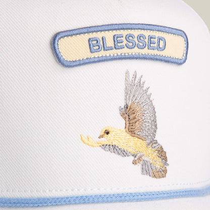 Close-up of the Goorin Bros. Pop Rocker Blessed trucker hat, featuring a "BLESSED" patch and an embroidered yellow and gray bird in flight.