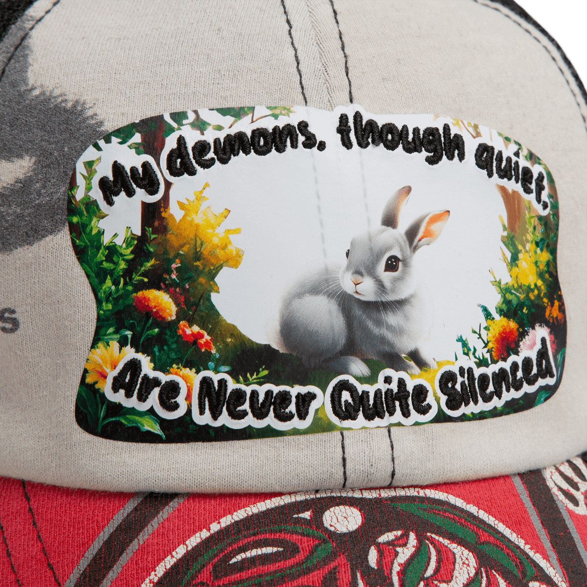 A close-up of the Lil Ronin hat by Goorin Bros., crafted from recycled tees, with a patch featuring a gray rabbit, vibrant plants, and the phrase "My demons, though quiet, are never quite silenced.