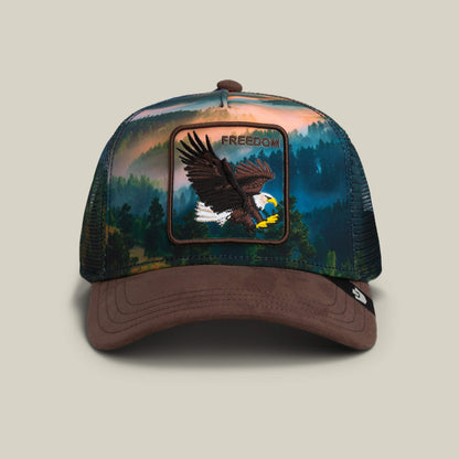 The Goorin Bros. Eagle In The Element hat in GROUND features a brown brim, mesh sides, and an eagle FREEDOM patch—ideal for fans of the classic eagle trucker hat style.