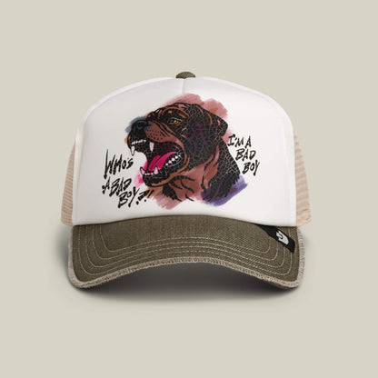 The Bad Boy Disruption trucker hat by Goorin Bros. features a hand-illustrated snarling Rottweiler and “WHO’S A BAD BOY?”/“I’M A BAD BOY” text on a white front panel, finished with a biscuit-colored bill.