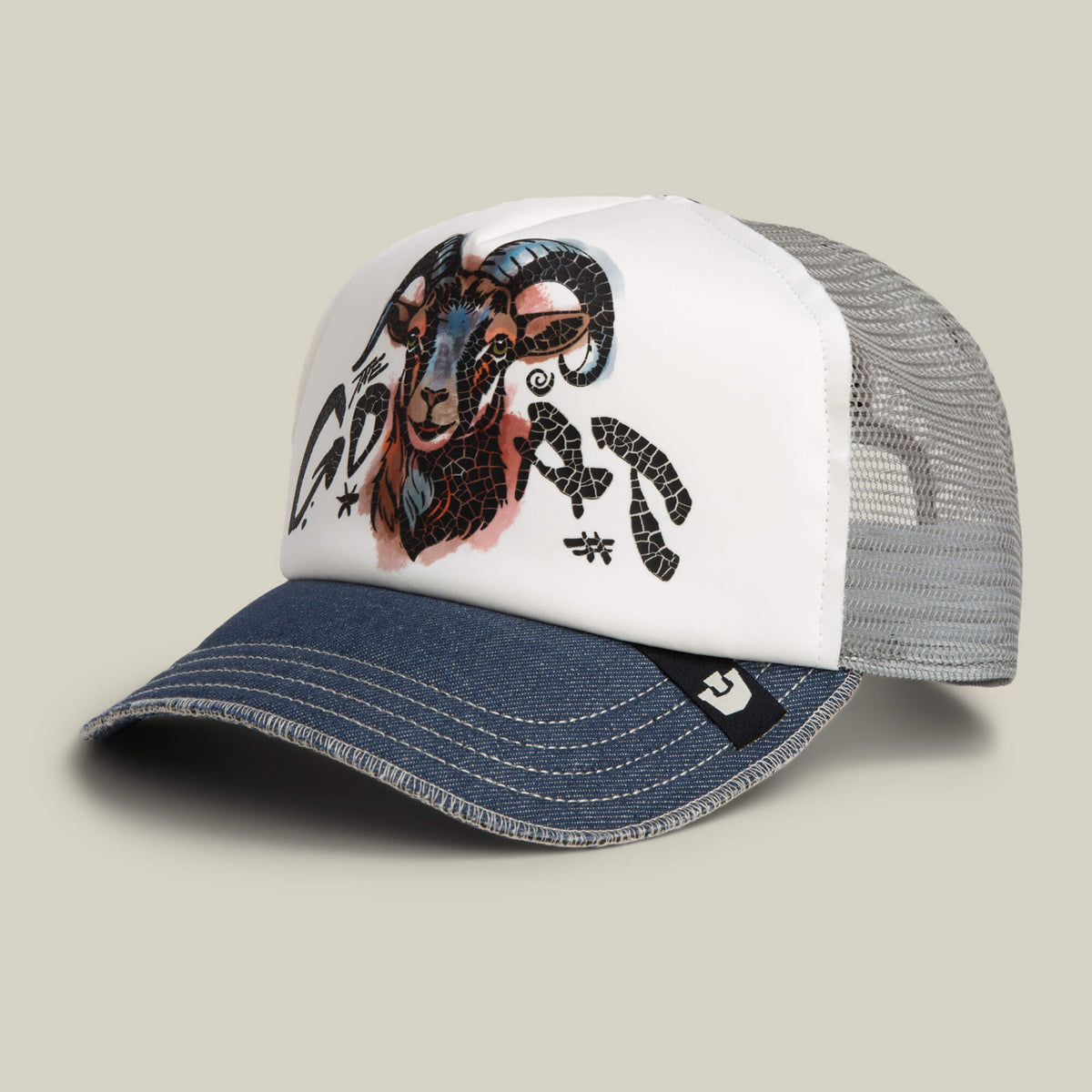 The Goorin Bros. Goat Disruption mesh trucker hat features a blue brim, white front panel, hand-illustrated goat with abstract black graphics, and is crafted from recycled materials.