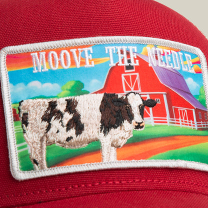 The Greener Grass - Moove the Needle hat by Goorin Bros. is a farm-inspired red trucker cap featuring a barn patch with a cow, rainbow, and "MOOVE THE NEEDLE" above the image.