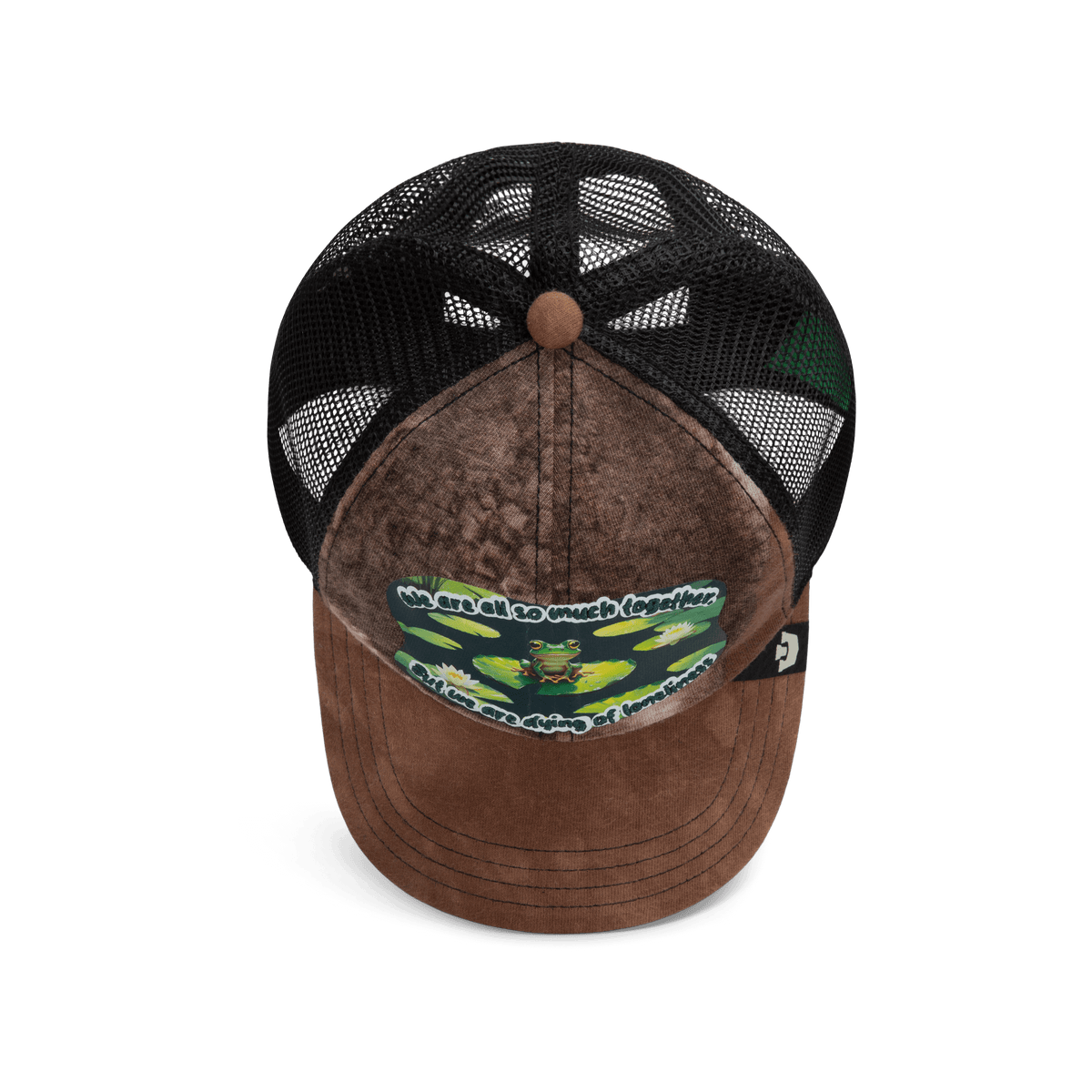 The Lil Sohei by Goorin Bros. is a brown and black trucker hat from the Storybook collection, featuring illustrated frogs, a mesh back, and the phrase: We are all so much together...but we are dying of loneliness.