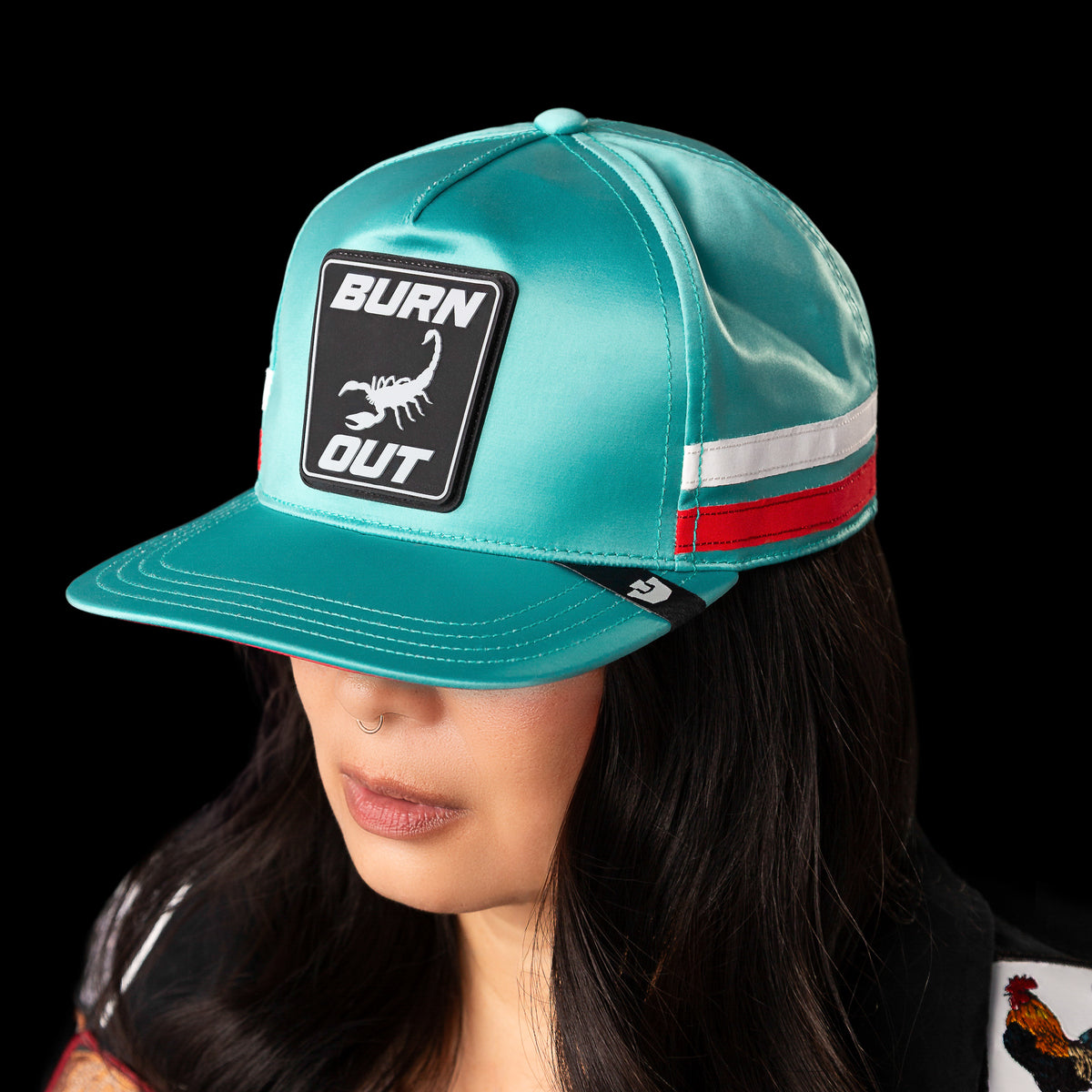 Inspired by racing, the Goorin Bros. Pole Position - Road Kill cap features turquoise fabric, chrome satin stripes, a black patch with a white scorpion, and “BURN OUT” text.