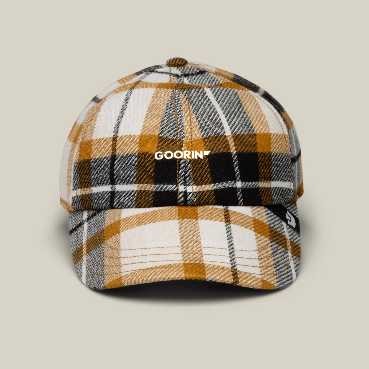 The Bespoke Wordmark V2 by Goorin Bros. is a papa cap in amber plaid with yellow, white, black, and gray patterns, "GOORIN" on the front, and a small black tag on the brim.