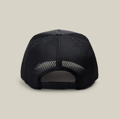 The NeoBrand STALLION trucker hat by Goorin Bros. is shown from the rear, displaying its black mesh back, matching snapback closure, and monochrome embroidery on a simple light beige background.