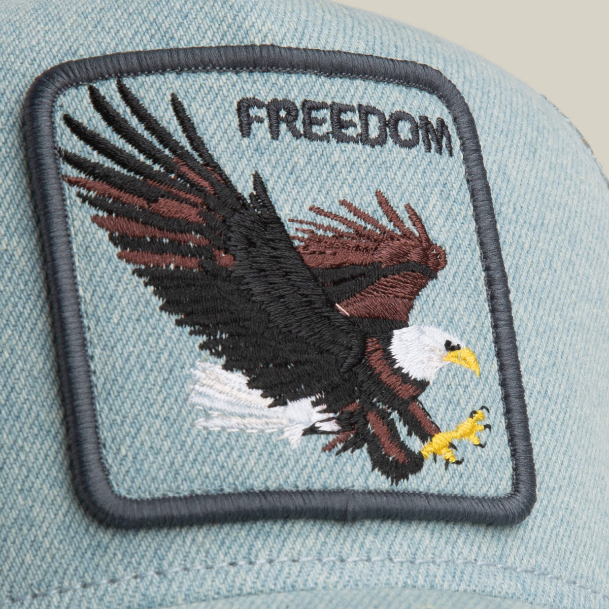 The Denim Eagle cap by Goorin Bros. is a light blue denim hat with a rectangular patch featuring an embroidered bald eagle and the word FREEDOM above it.