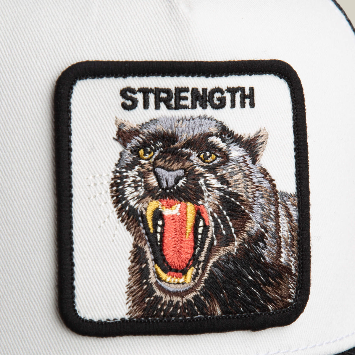 The Goorin Bros. Strength Panther Trucker features a snarling black panther and "STRENGTH" on a white background—ideal for adding bold style to your favorite cap or accessory.