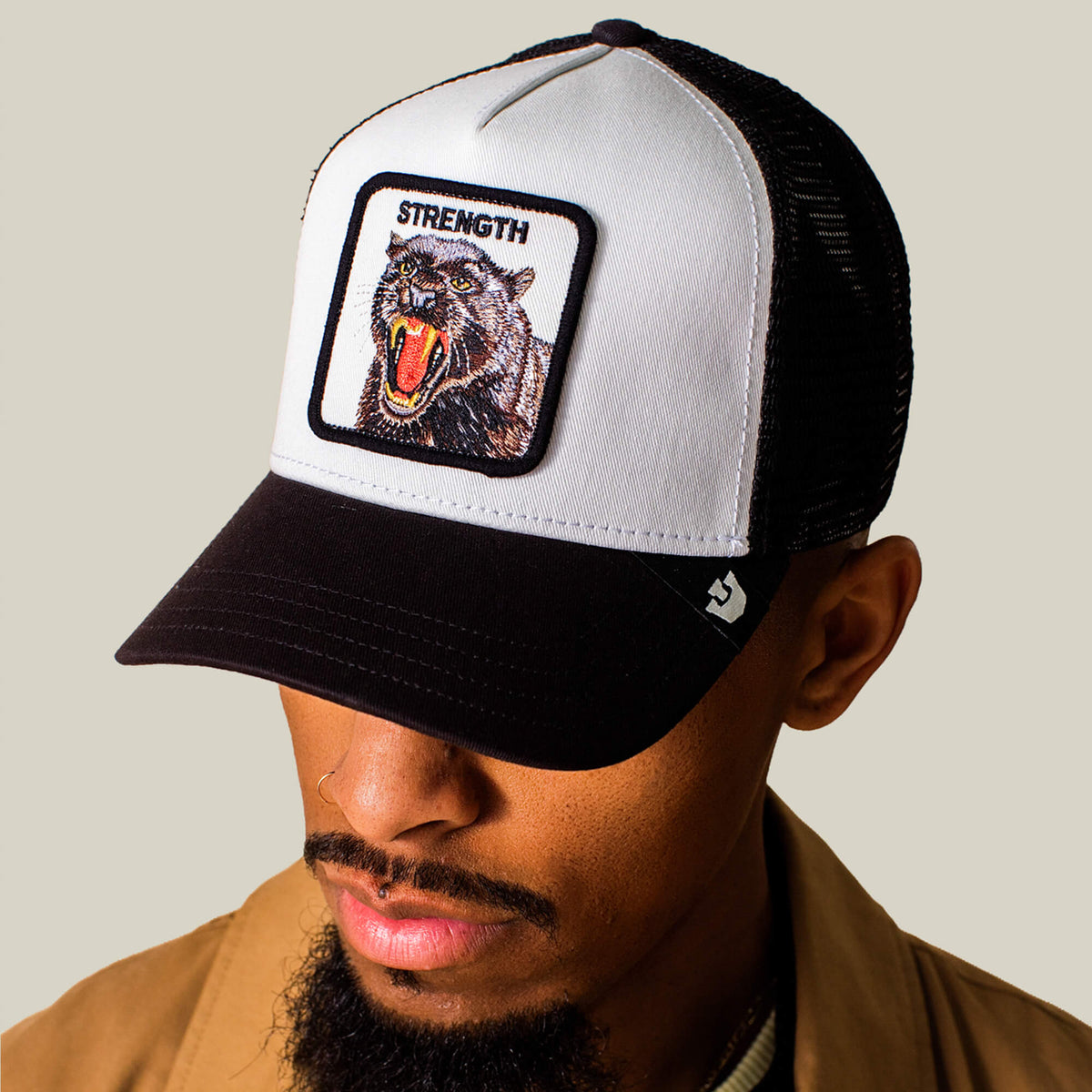 Man wearing the Goorin Bros. Strength Panther Trucker, a black and white cap with a bold panther patch labeled STRENGTH on the front.