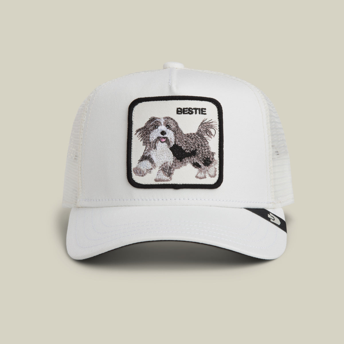 The Goorin Bros. Bestie Trucker in Dust features a white mesh design and a square patch with an embroidered dog and the word "BESTIE" above it.