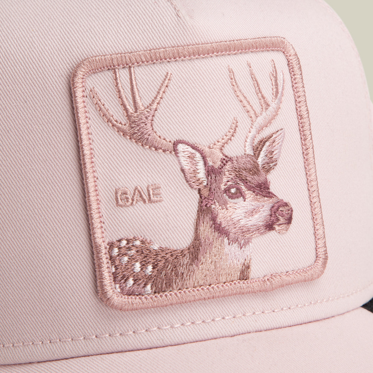 Close-up of the Goorin Bros. Mirage Bae cap, featuring a pink design with an embroidered deer patch and the word “BAE” in capital letters.