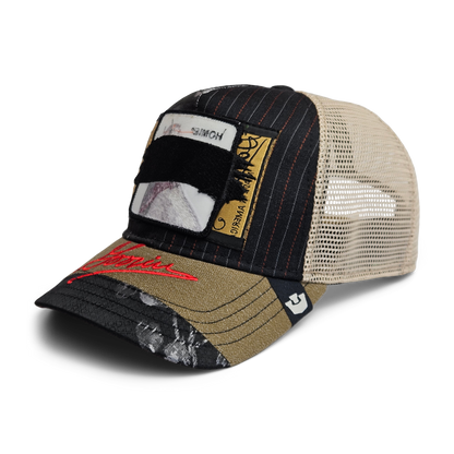 The Goorin Rework Trucker by Goorin Bros. is a limited edition trucker cap featuring a black and beige mesh back, patchwork design, red brim text, and unique stitched and printed patches made from recycled fabrics.