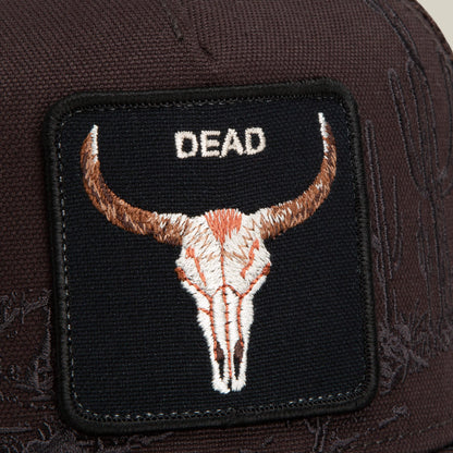 A close-up of the Goorin Bros. Badlands Skull patch, featuring an embroidered bull skull and the word "DEAD" in white letters on a dark brown fabric background.