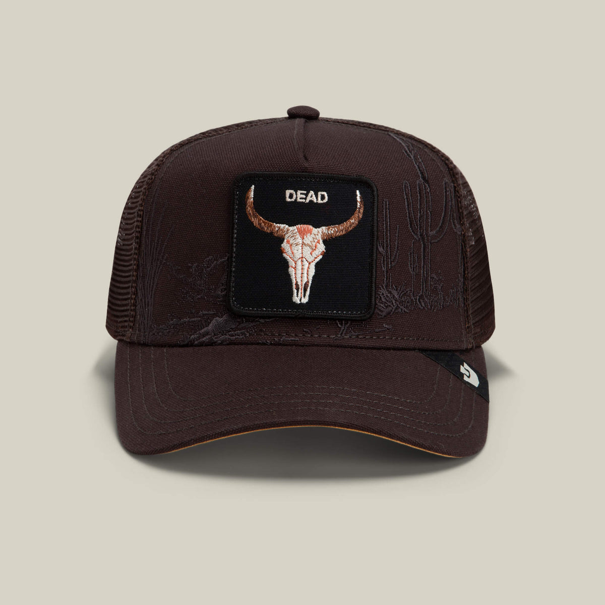 A "Ground" colored mesh trucker hat from Goorin Bros. called the Badlands Skull, featuring a front patch with a bull skull and the word DEAD, with subtle embroidered cactus illustrations on the cap.