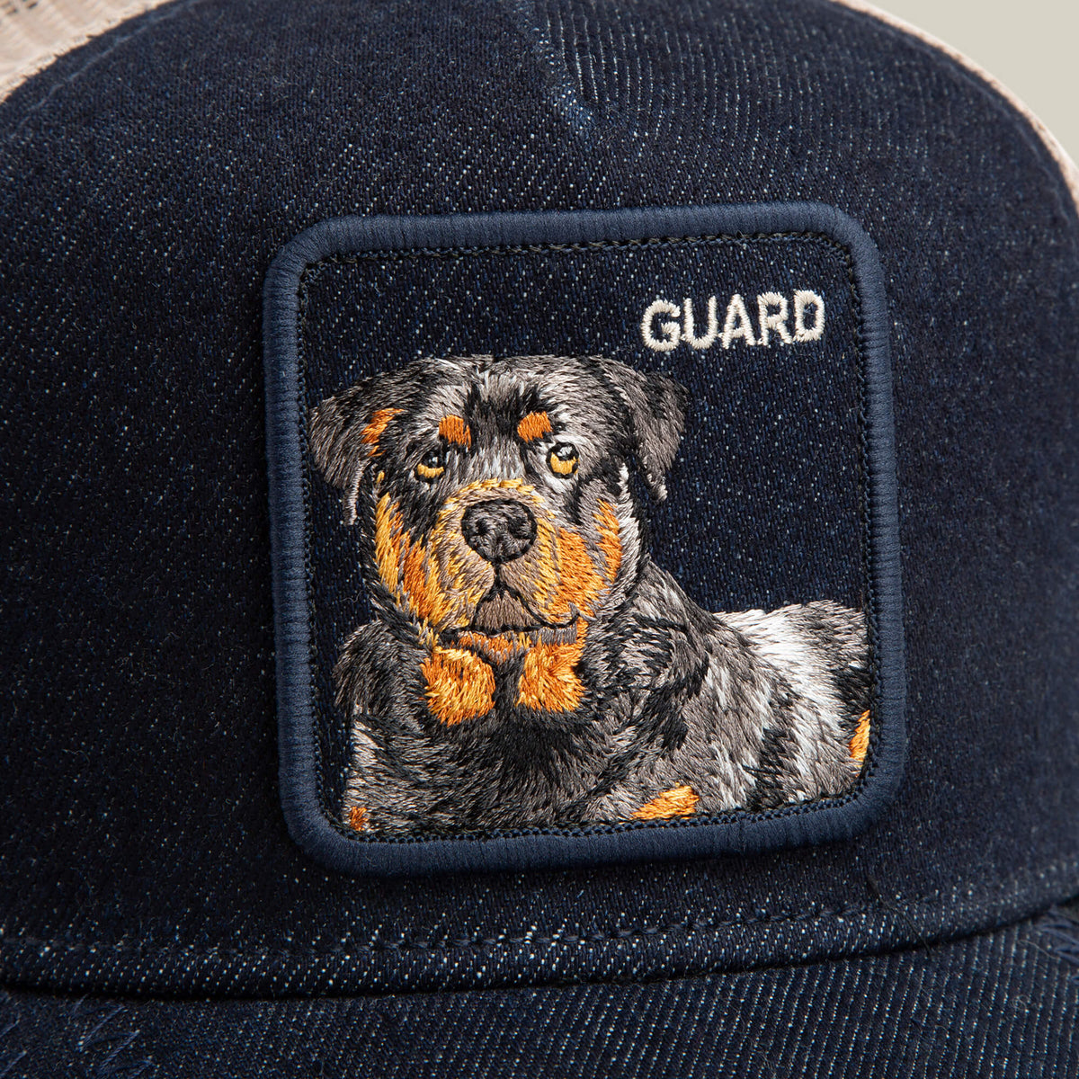 The Goorin Bros. Denim Guard is a navy blue trucker hat featuring a patch with an embroidered Rottweiler and the word "GUARD" in white above the dog's head.