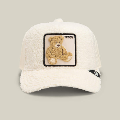 The Goorin Bros. Double Stuffed - Teddy cap in wax features a white textured teddy patch with a playful bear and the word "TEDDY" on the front. This cream sherpa trucker hat offers breathable mesh at the back and is finished with a small black side tag, blending comfort and charm in signature Goorin Bros. style.