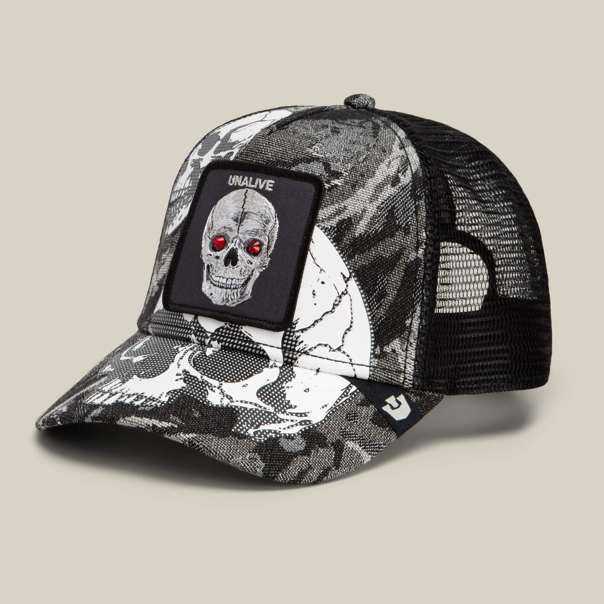 The Bone Head Unalive trucker hat by Goorin Bros. features a bold black and white skull print with red gem-like eyes, a breathable mesh back, and a signature UNALIVE patch.