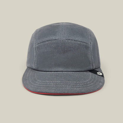 The North Boulder by Goorin Bros. is a gloss gray 5-panel camp cap with visible stitching, a slightly curved brim, and a small black tag on the left side, hand cut and sewn for quality, shown on a plain beige background.