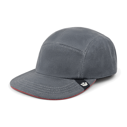 The North Boulder by Goorin Bros. is a grey cotton 5-panel camp cap with a slightly curved brim and a small black tag featuring a white logo on the left side, hand cut and sewn in the USA.