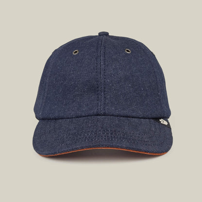 The Legend Ridge by Goorin Bros. is a dark denim baseball cap, made in the USA, with metal eyelets and a small black and white side tag, shown on a plain beige background.