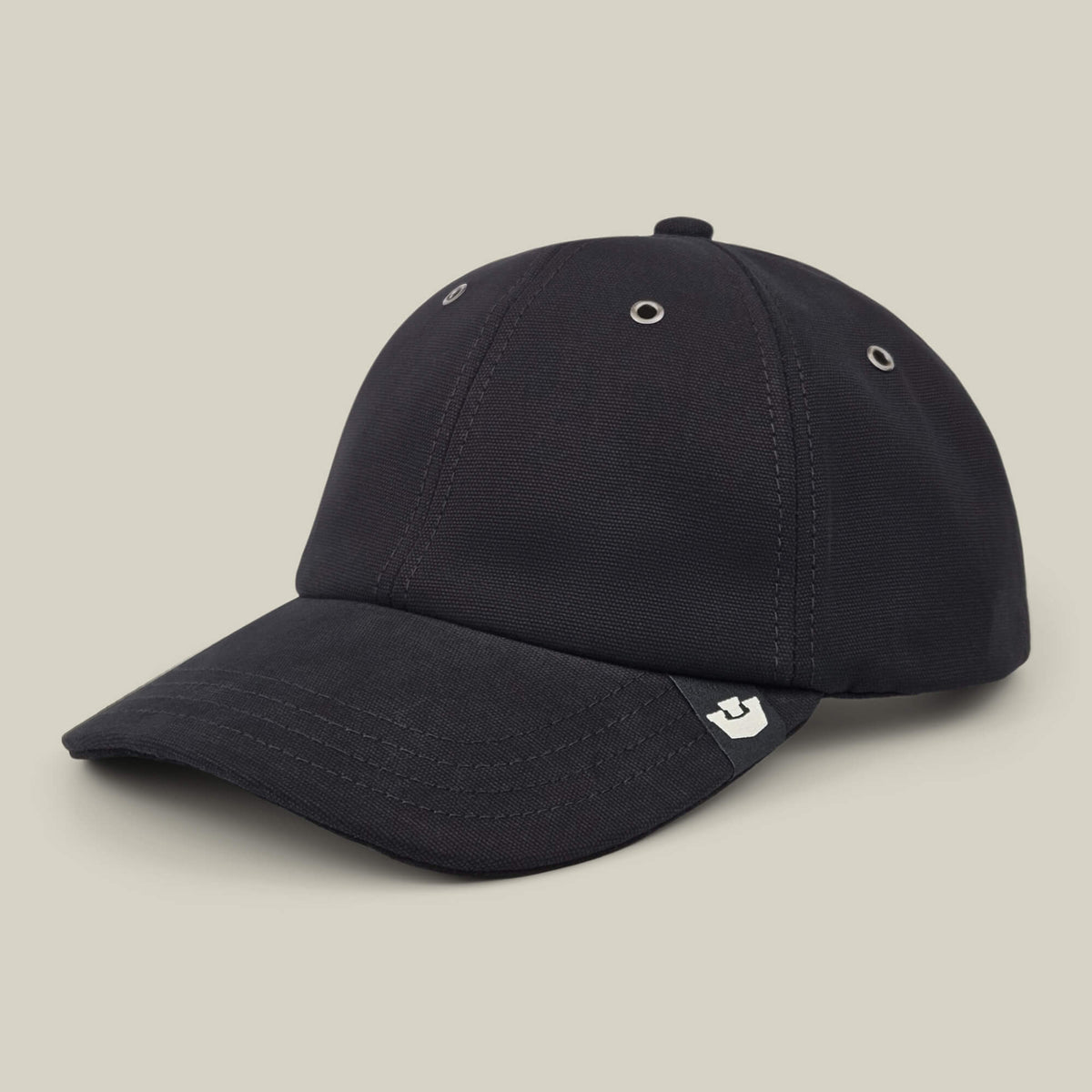 The Mineral Road black baseball cap by Goorin Bros. features mixed materials, a curved brim with metal eyelets, and a small white graphic tag on the left side of the brim, shown against a plain beige background.